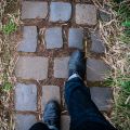 shot of feet of person walking on a cobbled pathway in what looks like a garden or nature path